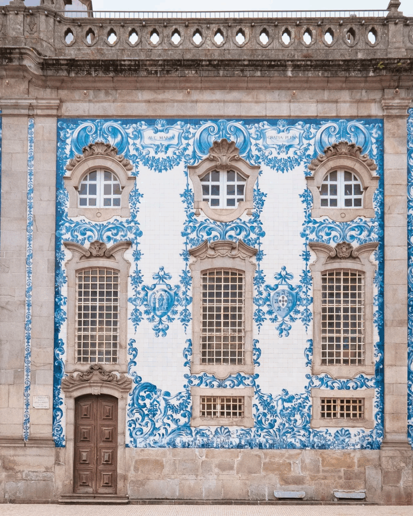 Ornate blue and white azulejo tile facade of Igreja do Carmo church in Porto featuring religious scenes with baroque stone window frames and decorative elements
