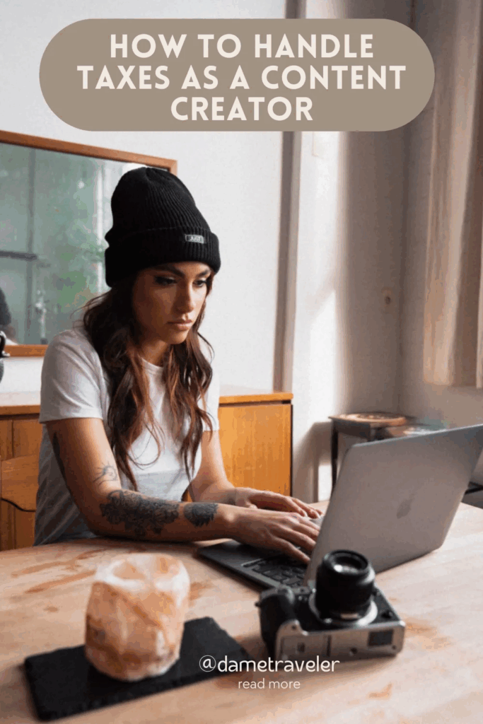 Female content creator working on laptop at desk with camera equipment. Text reads: How to Handle Taxes as a Content Creator, @dametraveler, read more