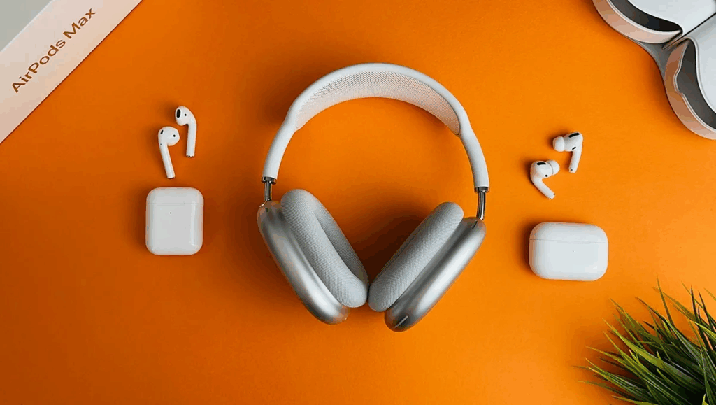 Silver Apple AirPods Max headphones and white AirPods Pro earbuds on an orange background, must-have travel tech essentials, and portable travel gadgets for flights