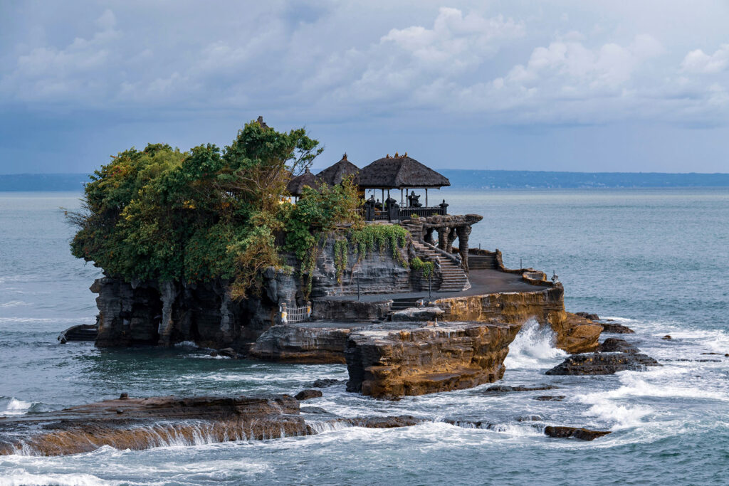 Tanah Lot temple on a rocky island surrounded by ocean waves in Bali, Indonesia.
