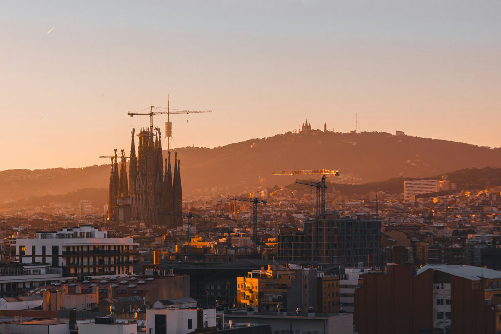 Barcelona skyline at golden hour featuring the Sagrada Família and surrounding cityscape bathed in warm sunset light.