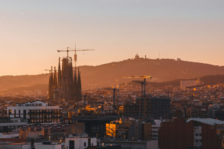 Barcelona skyline at golden hour featuring the Sagrada Família and surrounding cityscape bathed in warm sunset light.